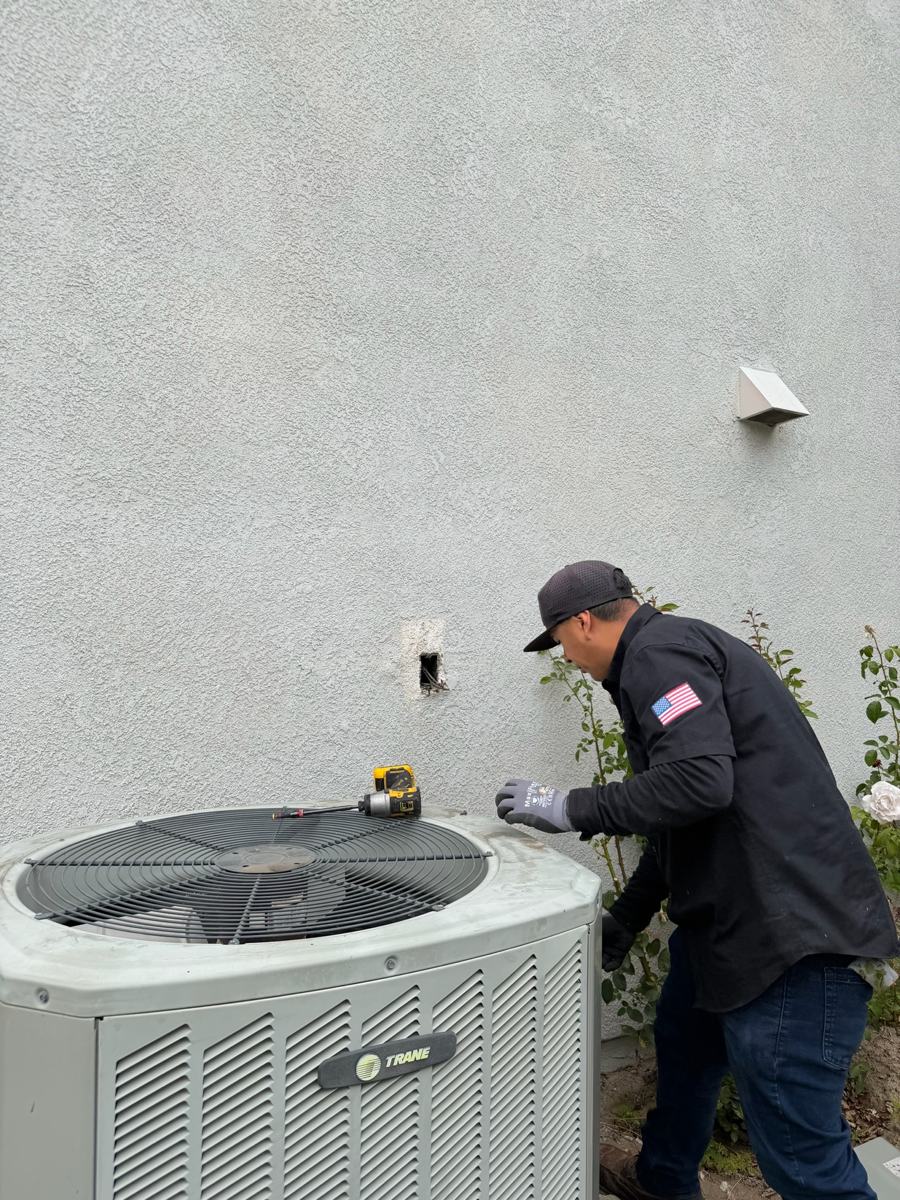 Technician working on top of an outdoor condenser