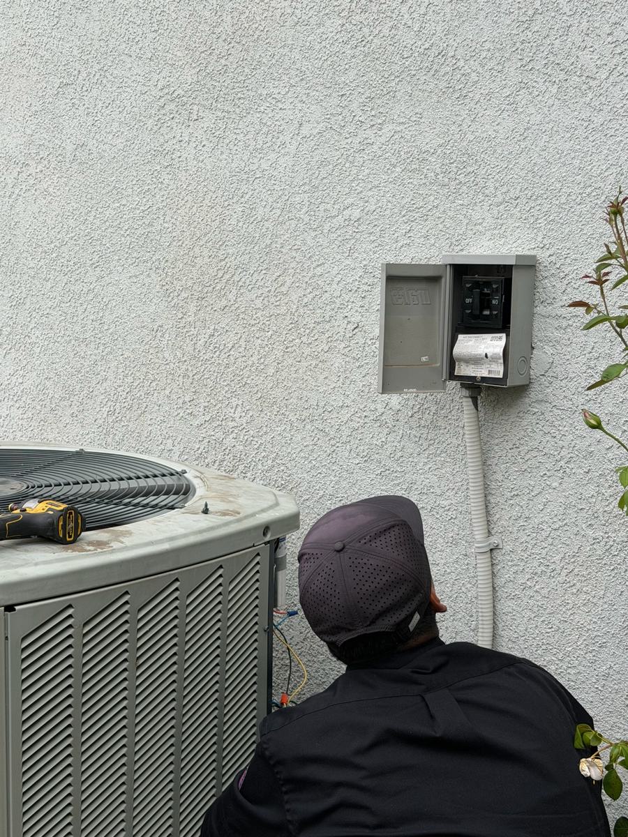Technician checking the wiring on an outdoor condenser