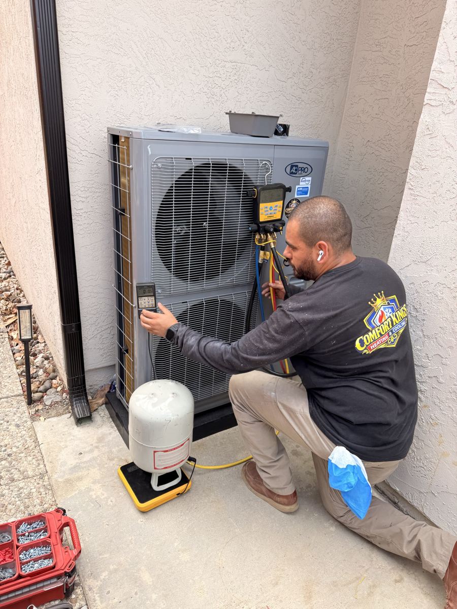 Technician reading refrigerant gauges on a heat pump