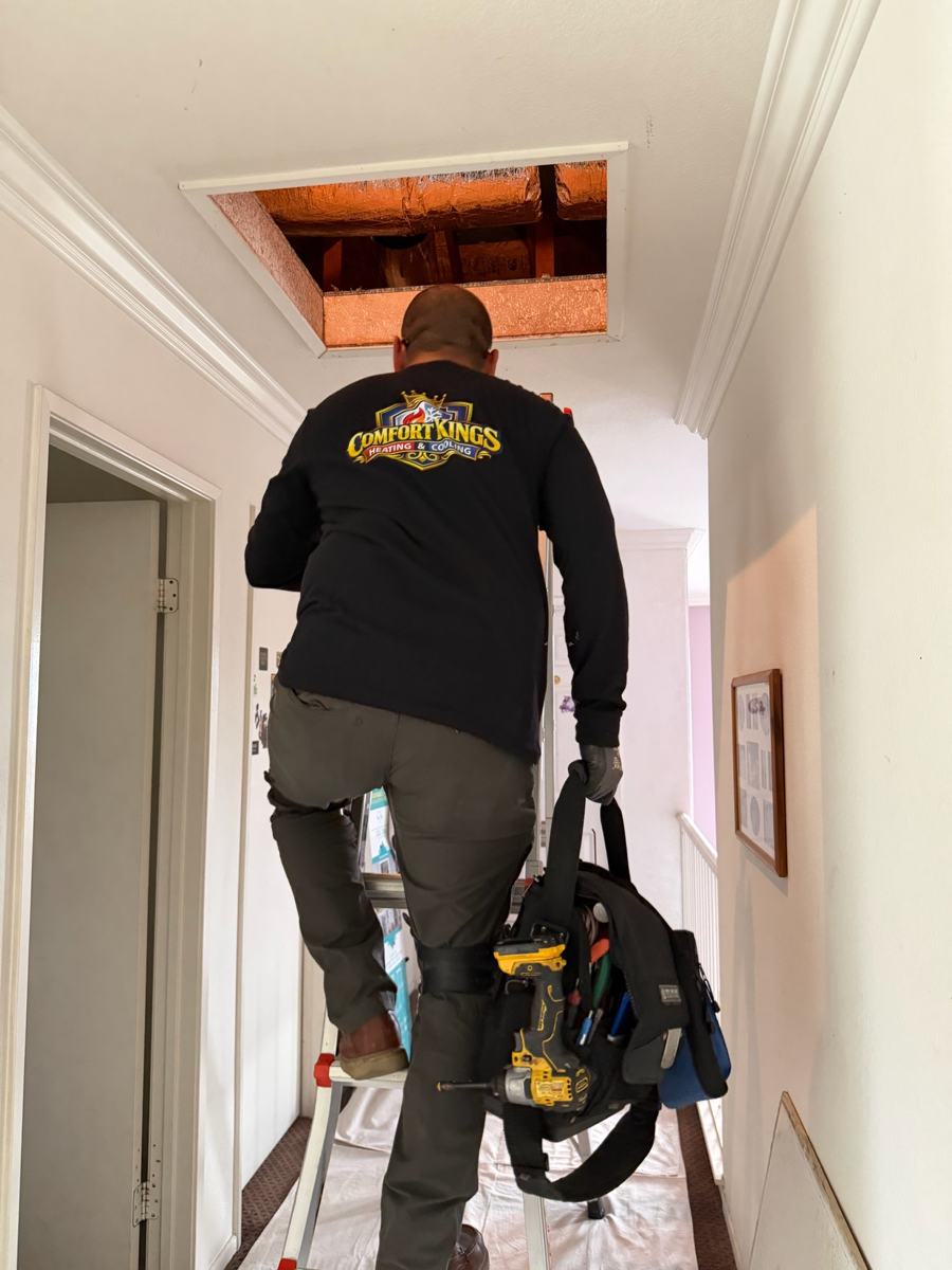 Technician climbing into an attic for a heating tune-up